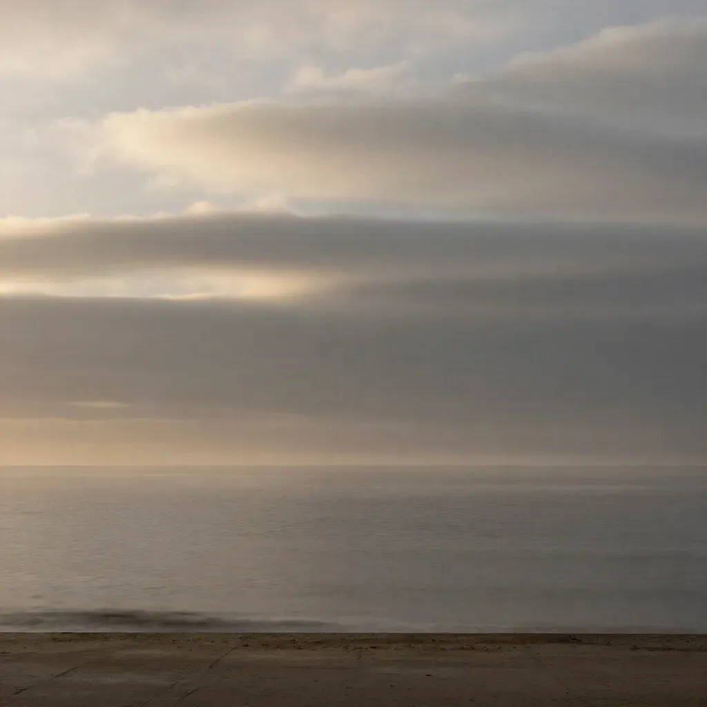 Misty Atlantic dawn horizon with a bright band of light over calm sea and concrete edge